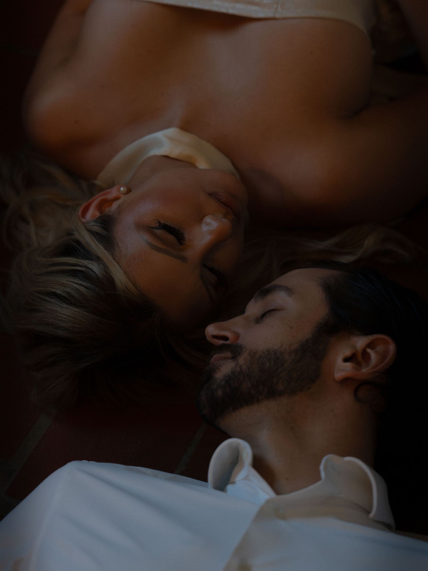 Couple lying on floor gazing at each other in intimate overhead portrait shot.