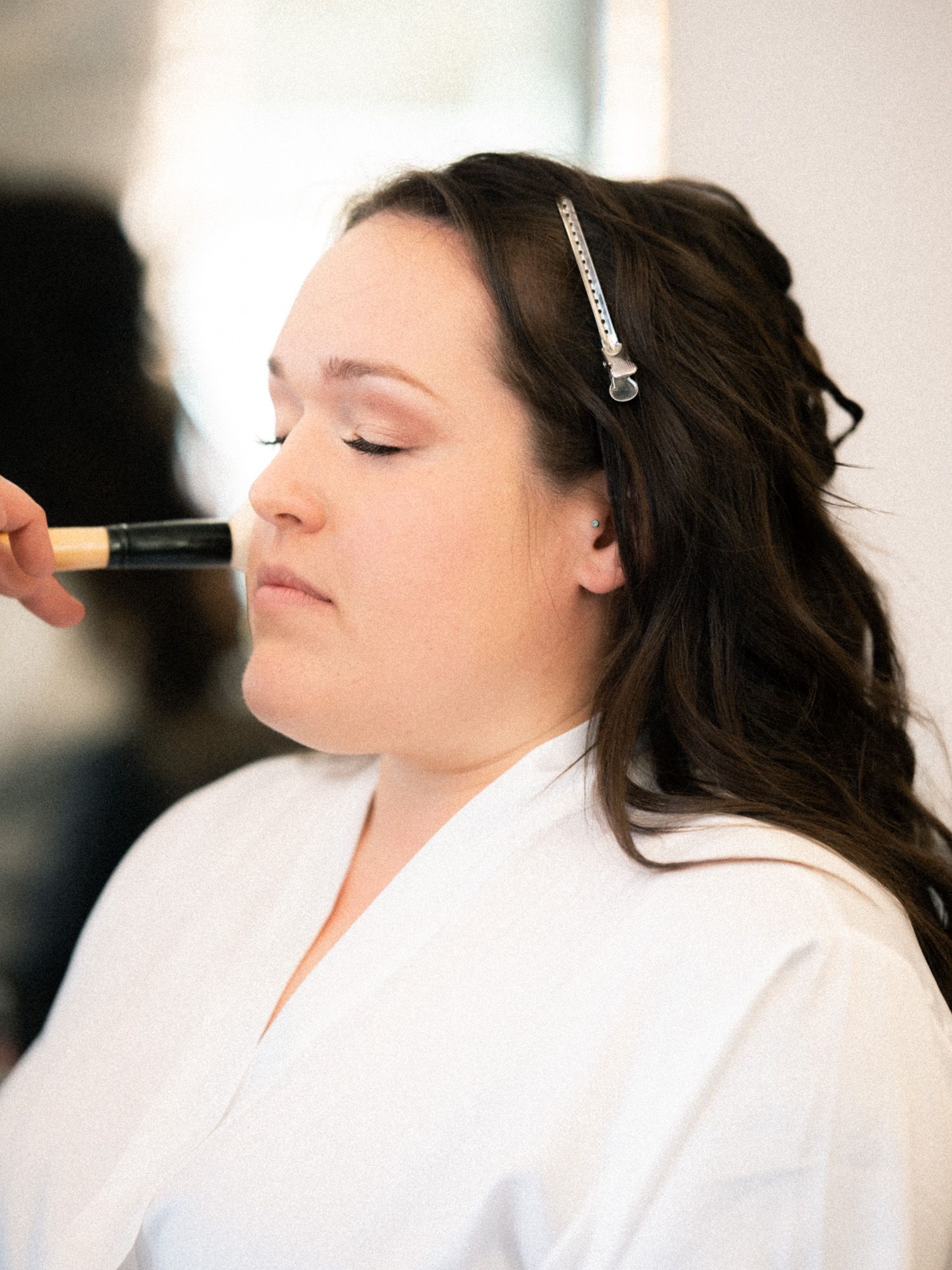 A person in a white robe relaxes with eyes closed during a spa or beauty treatment session.