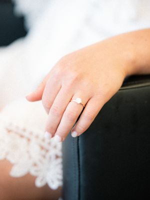 Close-up of a delicate white lace veil draped over dark furniture showing intricate floral patterns.