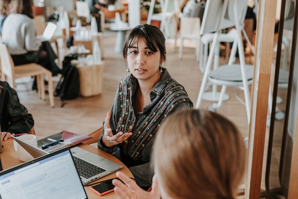 Two people having a business meeting at a table with laptops in a bright indoor space.