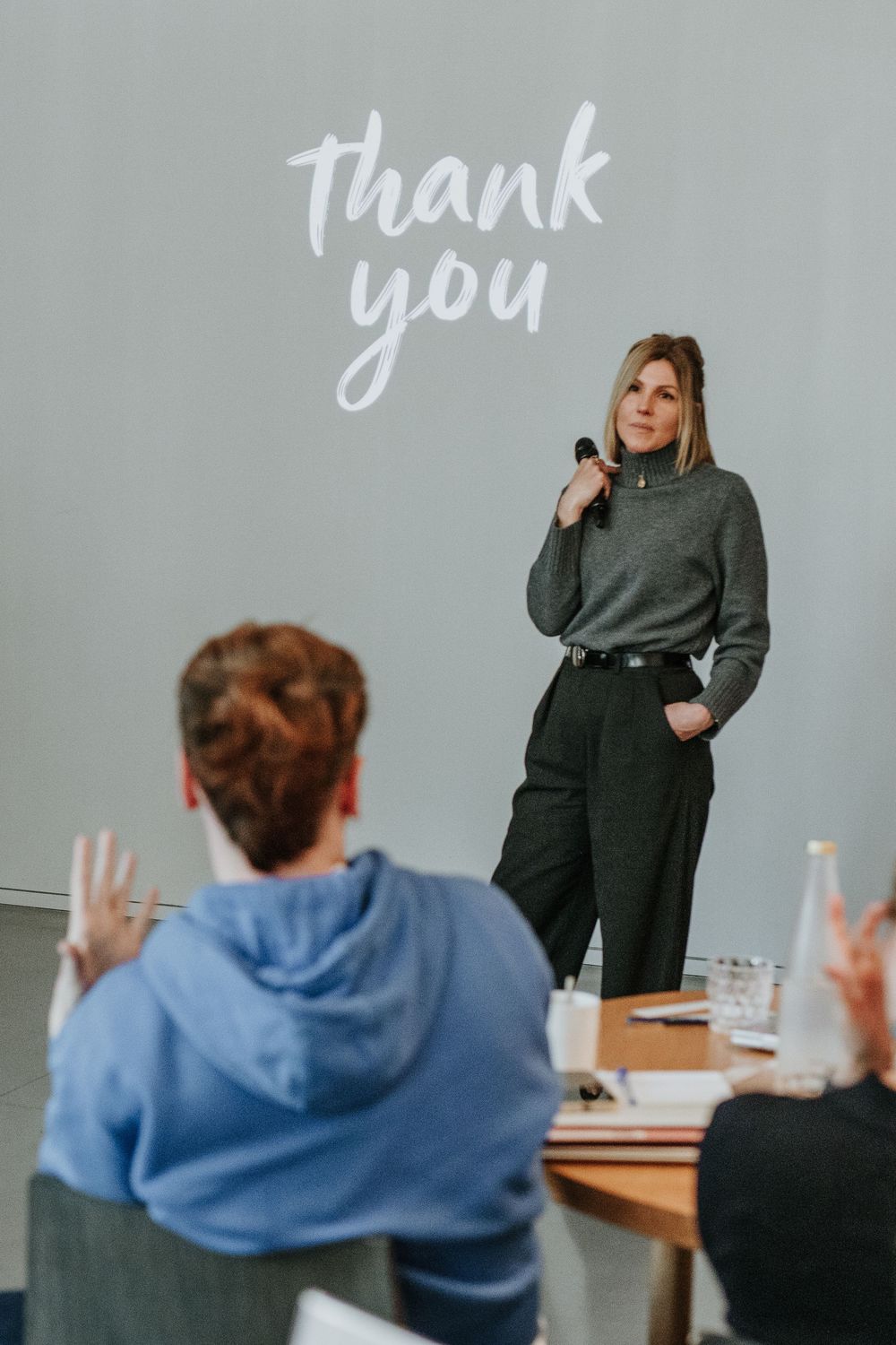 A sequence of four images showing a person in a blue hoodie writing 'thank you' on a classroom whiteboard.