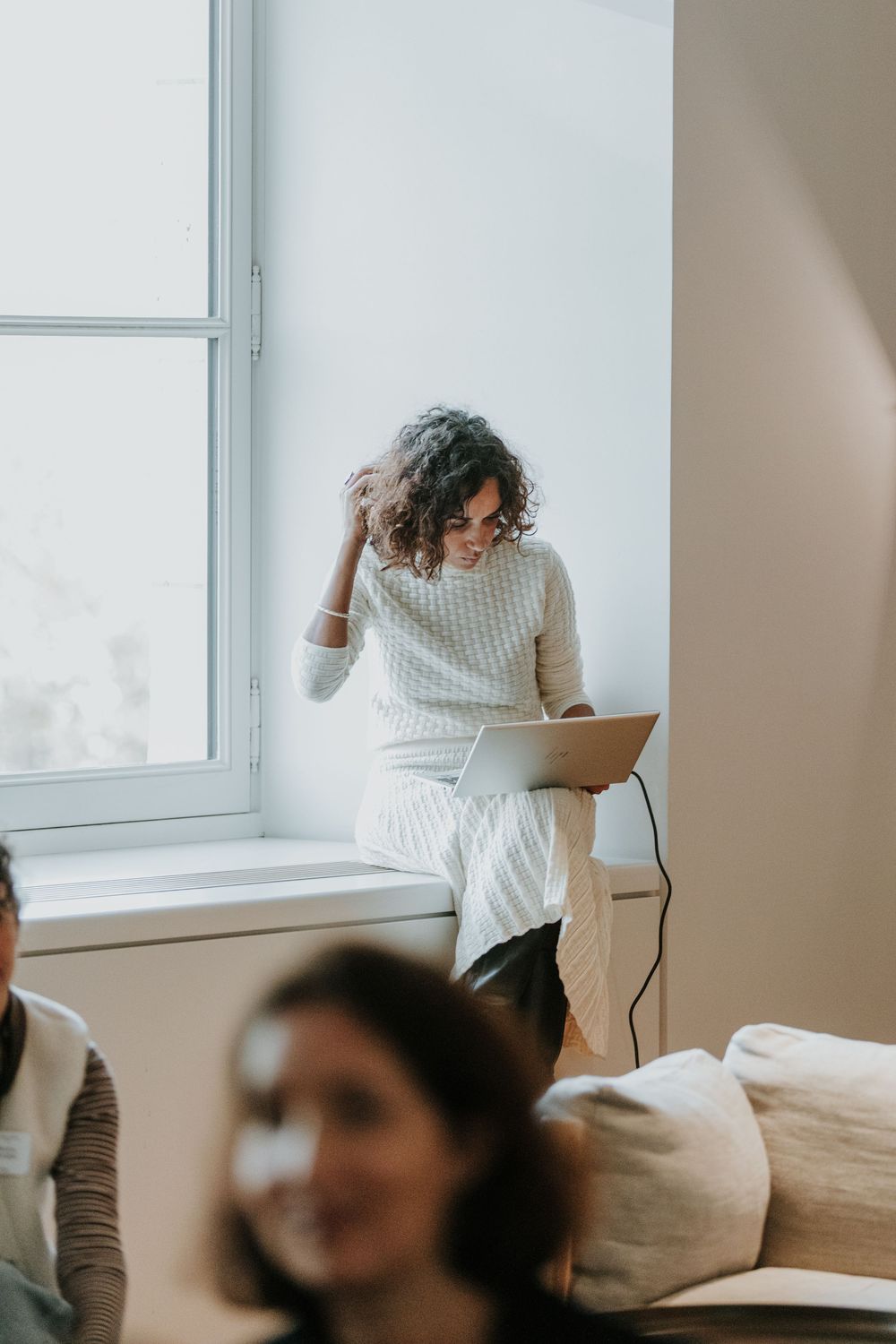 A person in a white sweater moves through a bright minimalist room in a sequence of candid lifestyle shots.