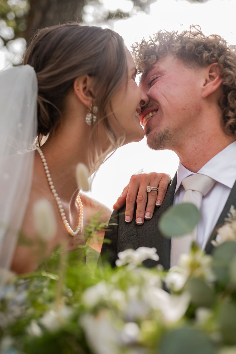 Romantic close-up sequence of a bride and groom kissing in a garden setting with white flowers in the foreground.