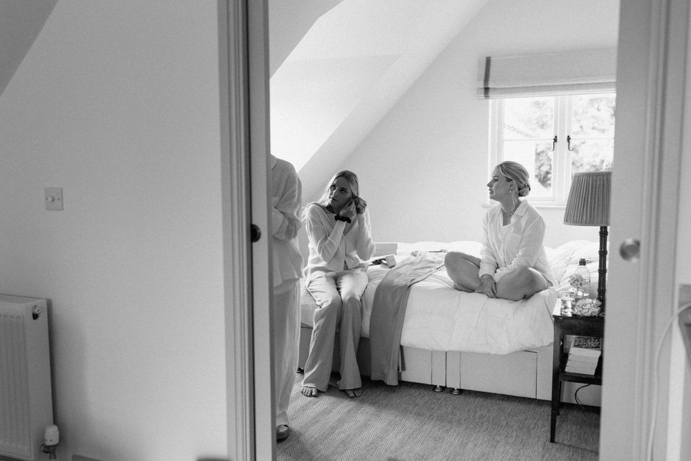 Black and white candid moment during wedding preparation in a bedroom.