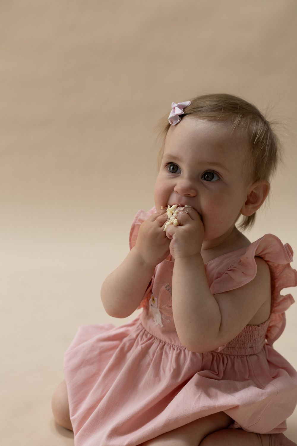 A baby eating cake during a cake smash photography session for a1st birthday in Bedfordshire.