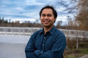 Portrait by waterfront with snowy landscape in background.