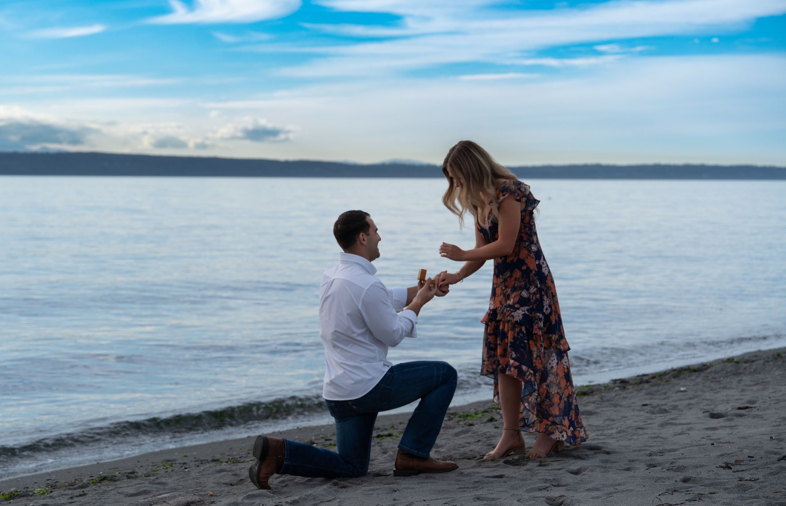 A proposal scene unfolds across six photos showing a couple on a scenic beach at sunset with tranquil ocean waters.