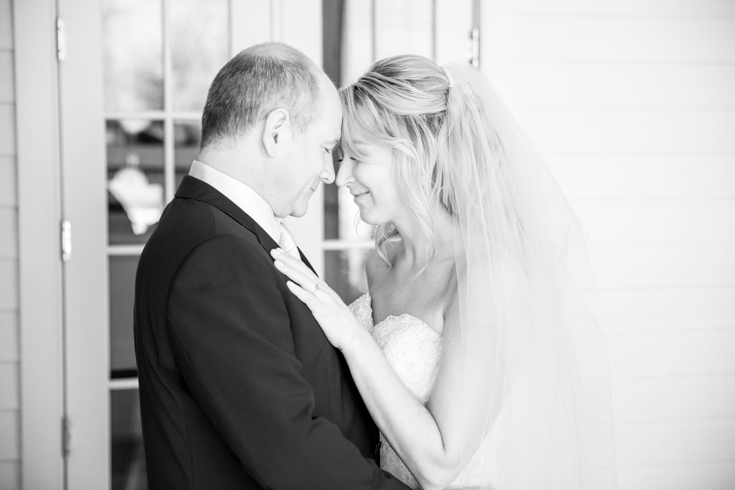Black and white intimate moment between newlyweds sharing a tender moment against a wall.