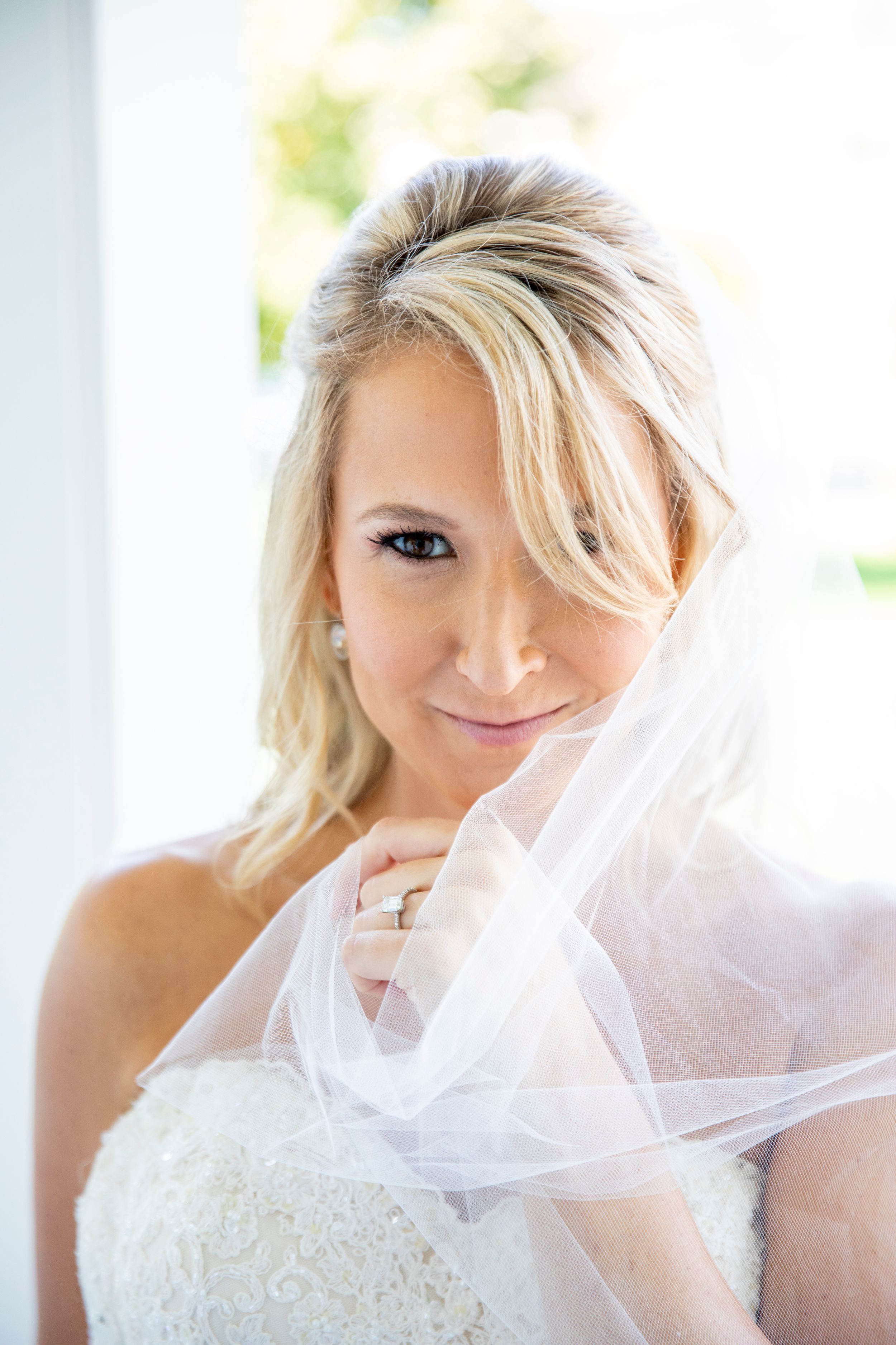 Elegant bridal portrait showing delicate lace dress and flowing veil details.