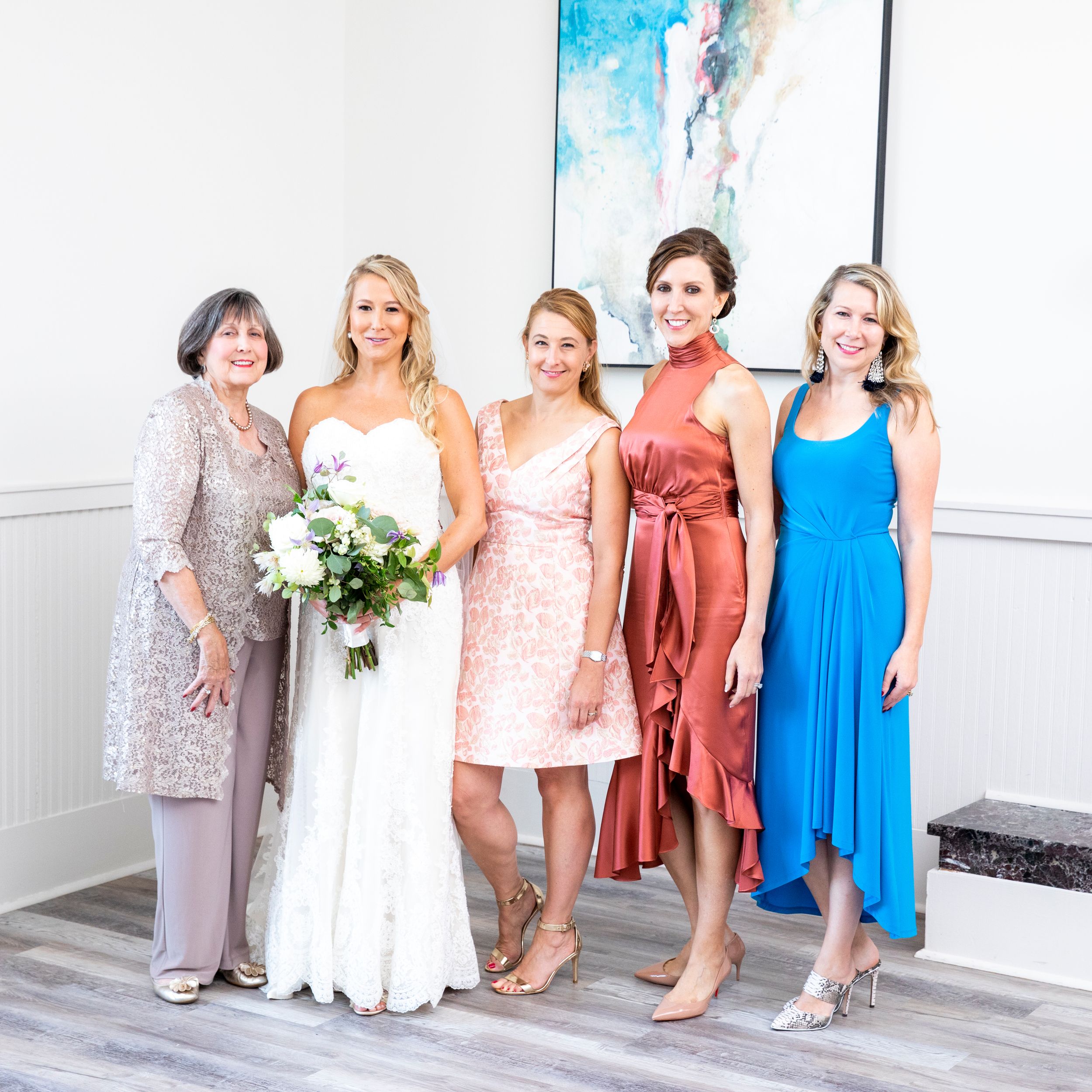 Wedding party group photo featuring coordinated dresses in various colors.