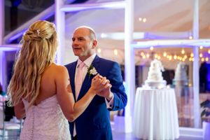Romantic first dance under purple lighting at an elegant wedding reception venue.