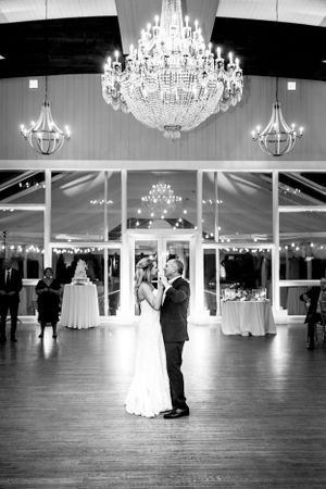 Elegant ballroom wedding dance under crystal chandeliers captured in black and white.