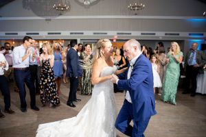 Wedding couple dancing together on the dance floor surrounded by guests.