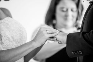 Close-up black and white shot of hands exchanging wedding rings during ceremony.