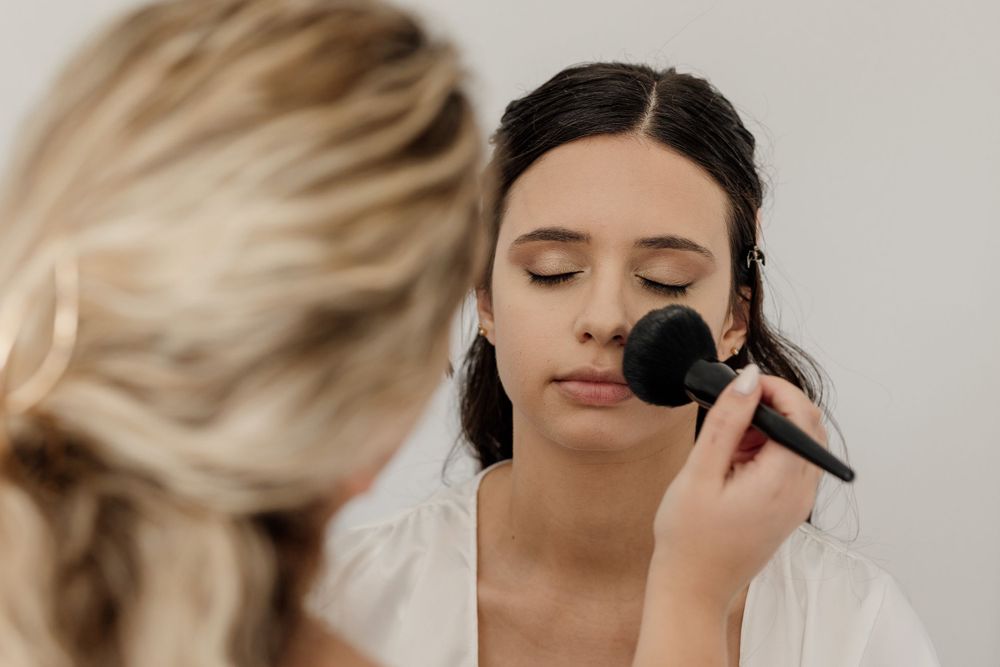 Makeup artist applying cosmetics to a client's face during a beauty session.