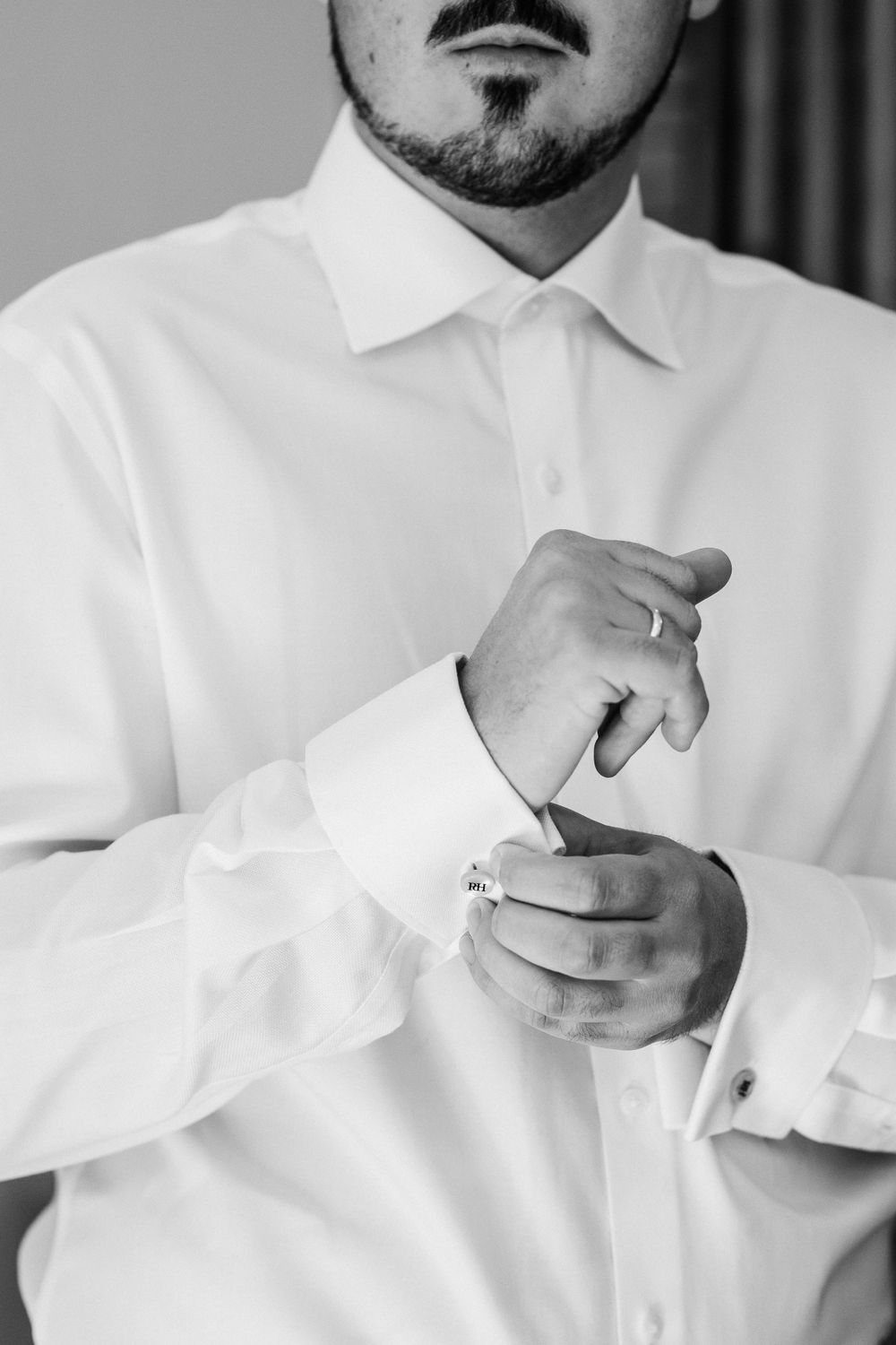 Close-up of hands adjusting white shirt cuffs before a formal event.