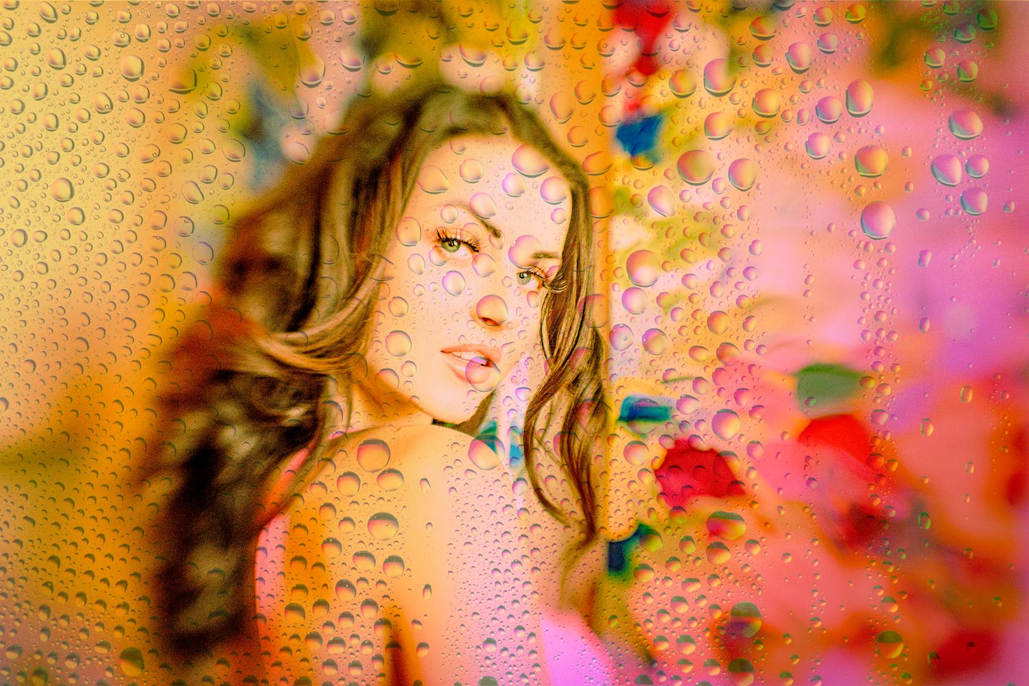 Artistic portrait through glass with colorful water droplets and bokeh effects.