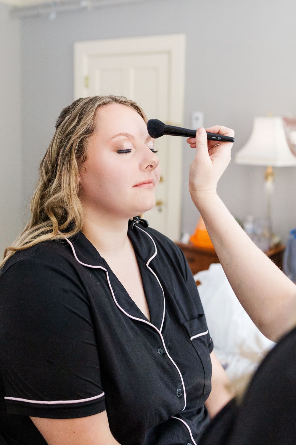 Getting ready scene with makeup application in black and white trimmed robe.