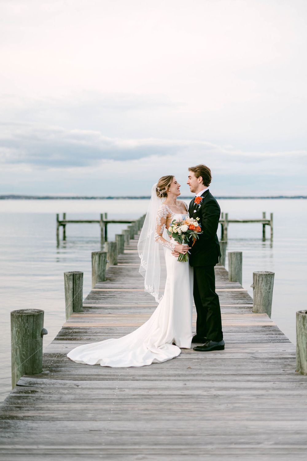A romantic wedding photo sequence on a wooden dock over calm waters with the couple sharing intimate moments.