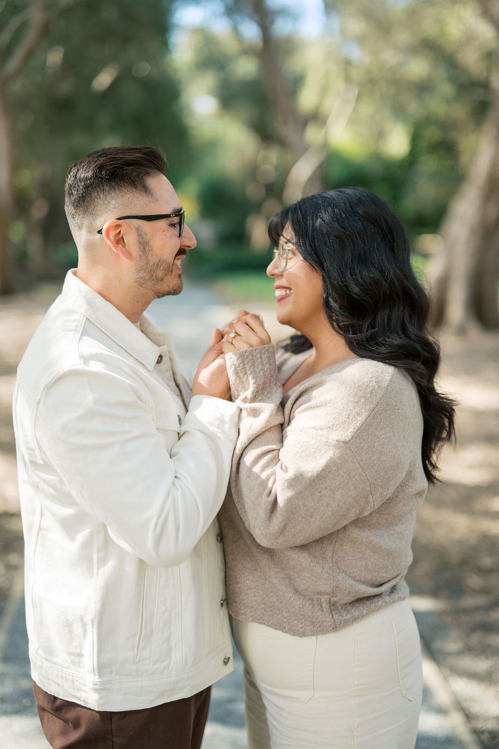 A romantic couple in coordinating cream and beige outfits share joyful moments together outdoors in a natural setting.