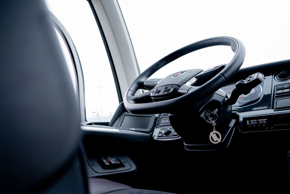 Modern vehicle dashboard and steering wheel interior shot in dramatic lighting.
