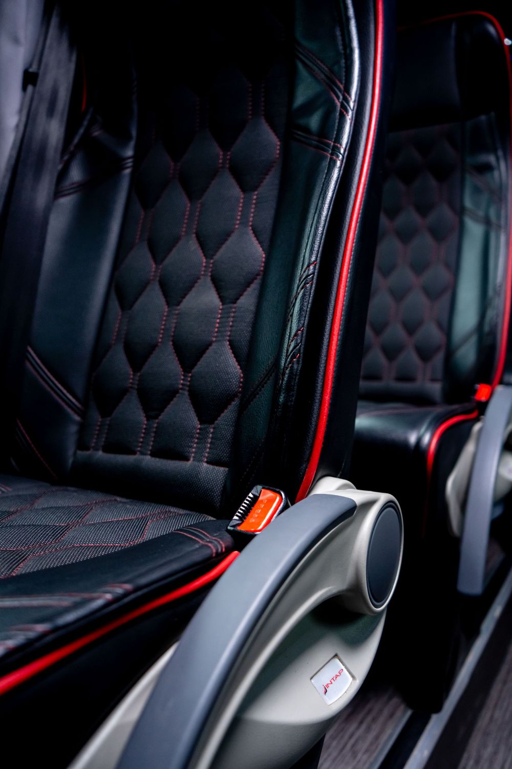 Luxury vehicle seats with diamond-stitched upholstery and red accent lighting.