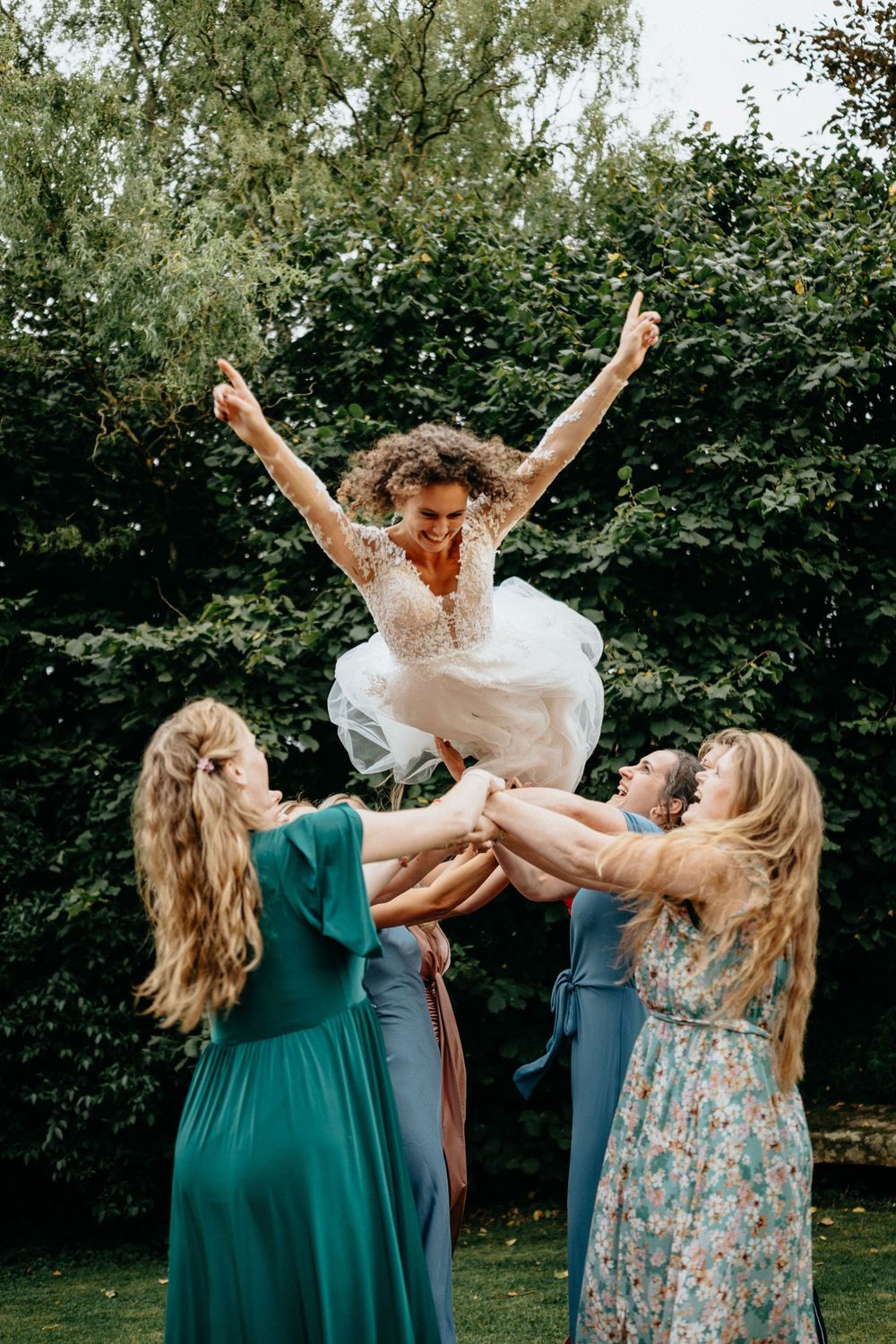 De bruid wordt omhoog gegooid door haar vriendinnen waardoor ze hoog door de lucht vliegt