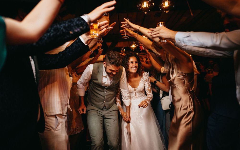 Een bruidspaar loopt door een erehaag gemaakt door de gasten op hun avondfeest