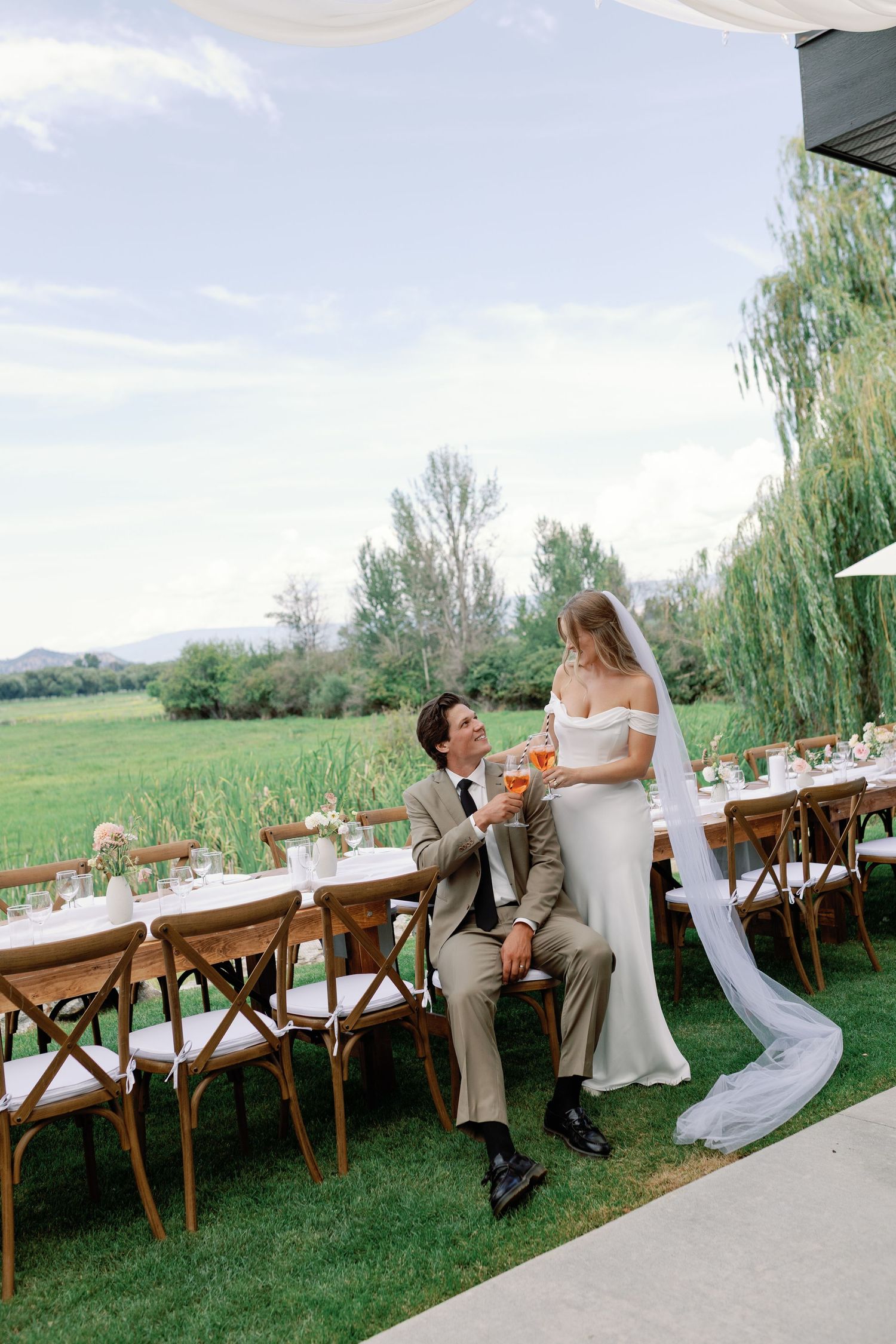 Elegant outdoor wedding ceremony setup with lush pink and burgundy floral arrangements against a vineyard backdrop.