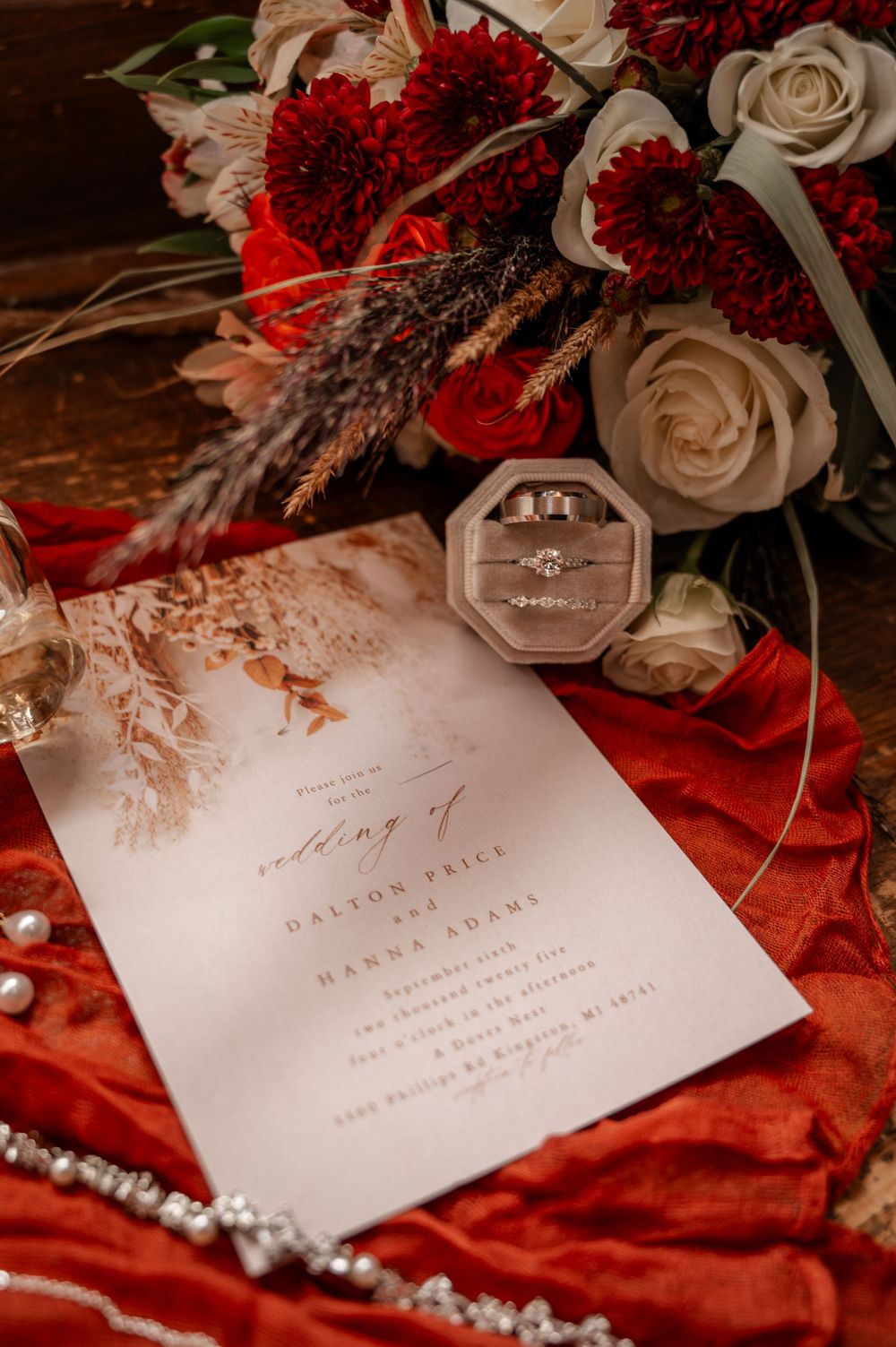 Wedding invitation for Dalton Price and Hanna Adams with diamond rings and red floral bouquet.