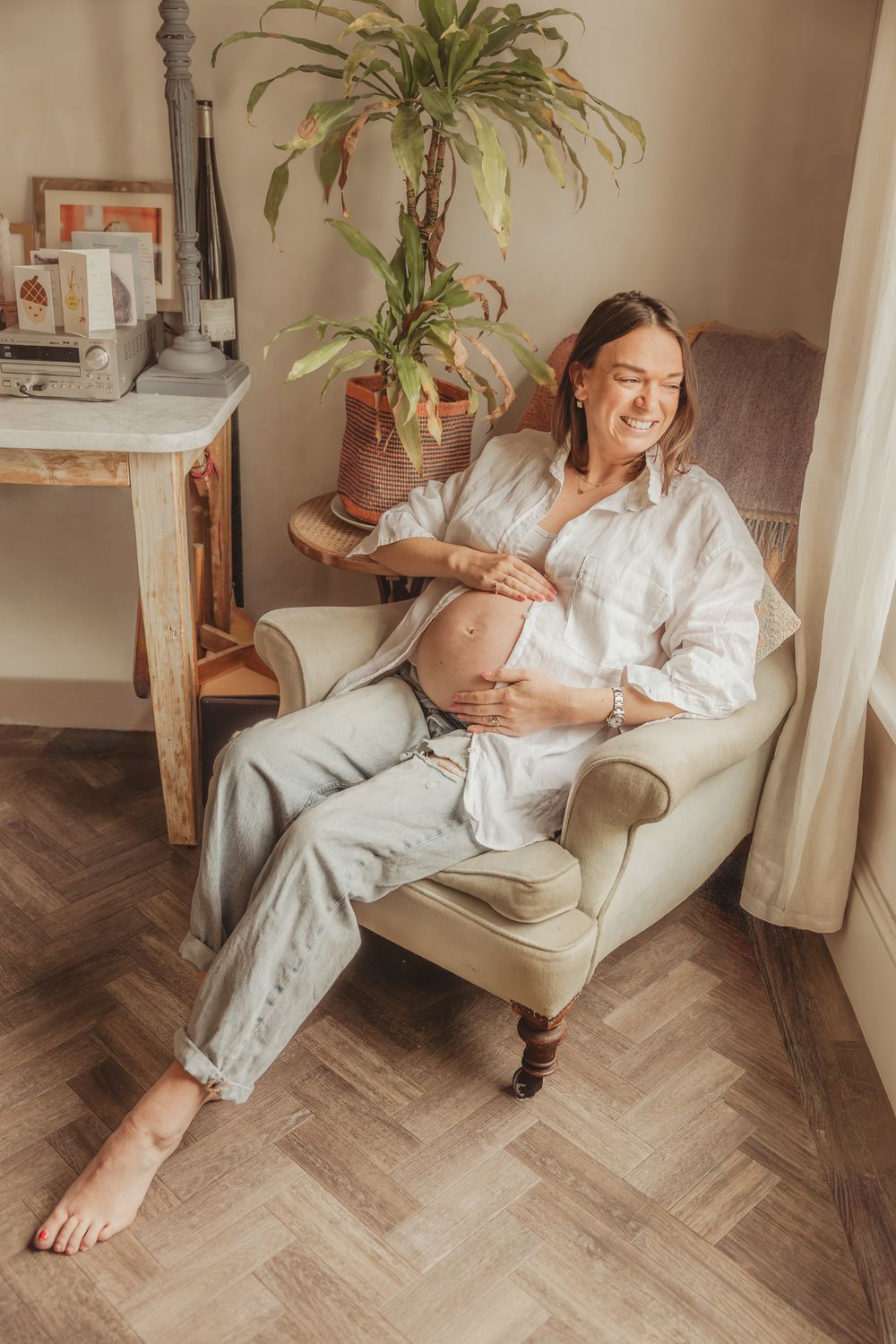 Relaxed lifestyle scene showing person in white loungewear reclining on vintage armchair at home.