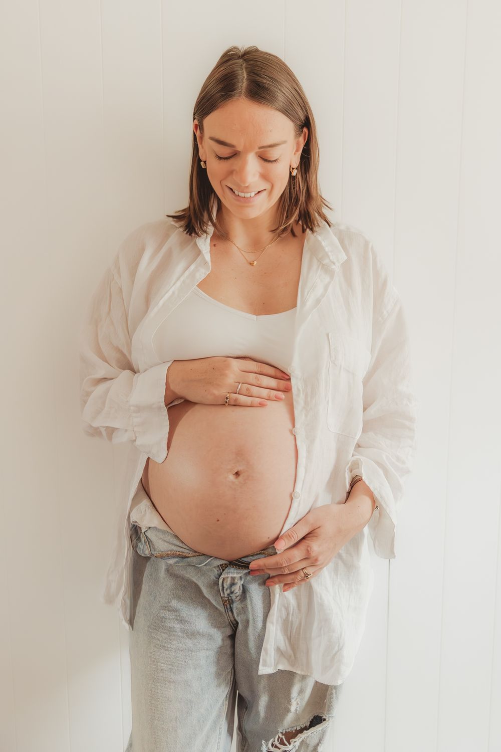 A series of maternity photos showing a pregnant belly in a white shirt and jeans against a light background.