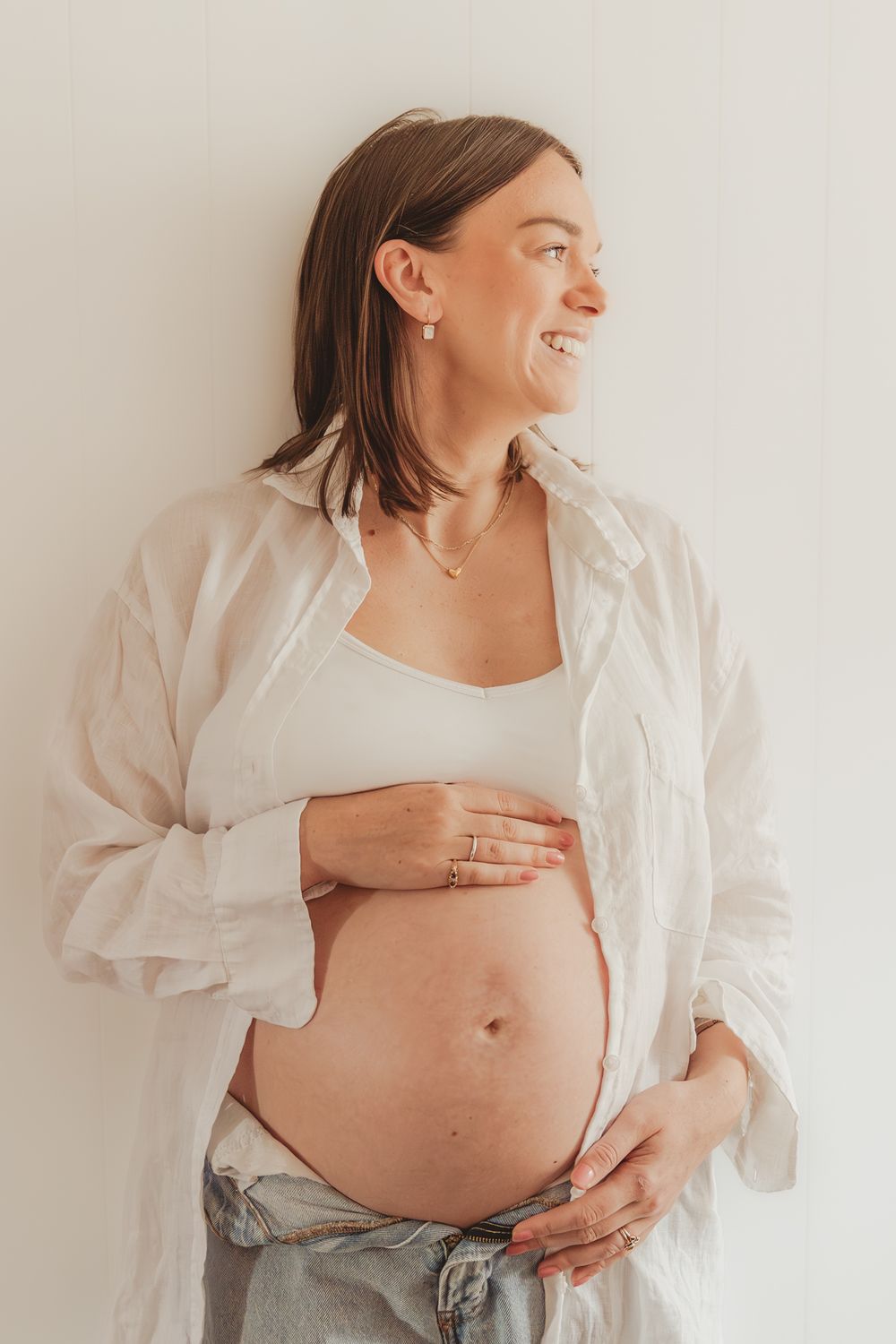 A series of pregnancy progression photos showing a growing baby bump with a white button-down shirt and jeans.