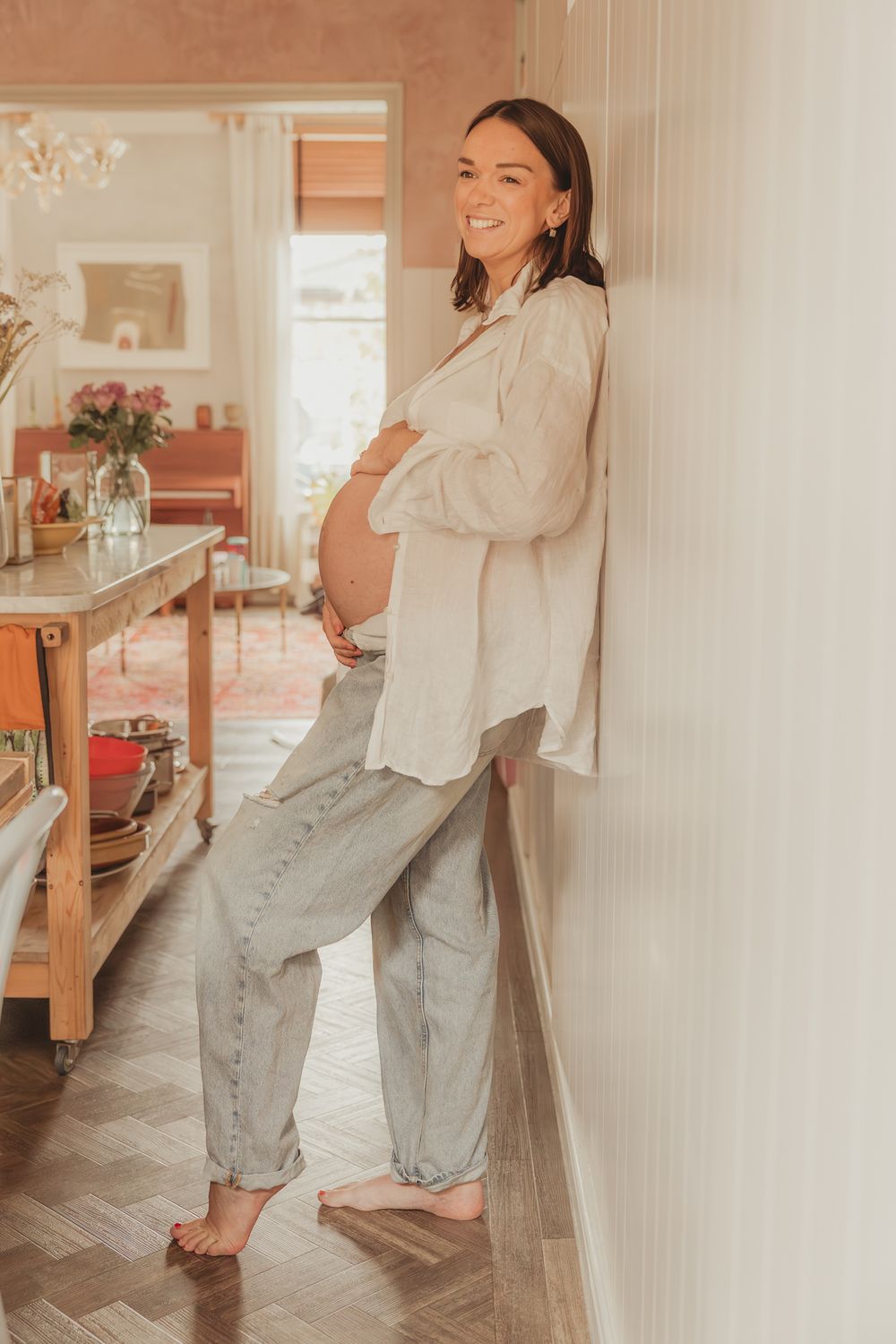 A series of four lifestyle photos showing someone wearing a white button-down shirt and light-wash jeans in a bright room.