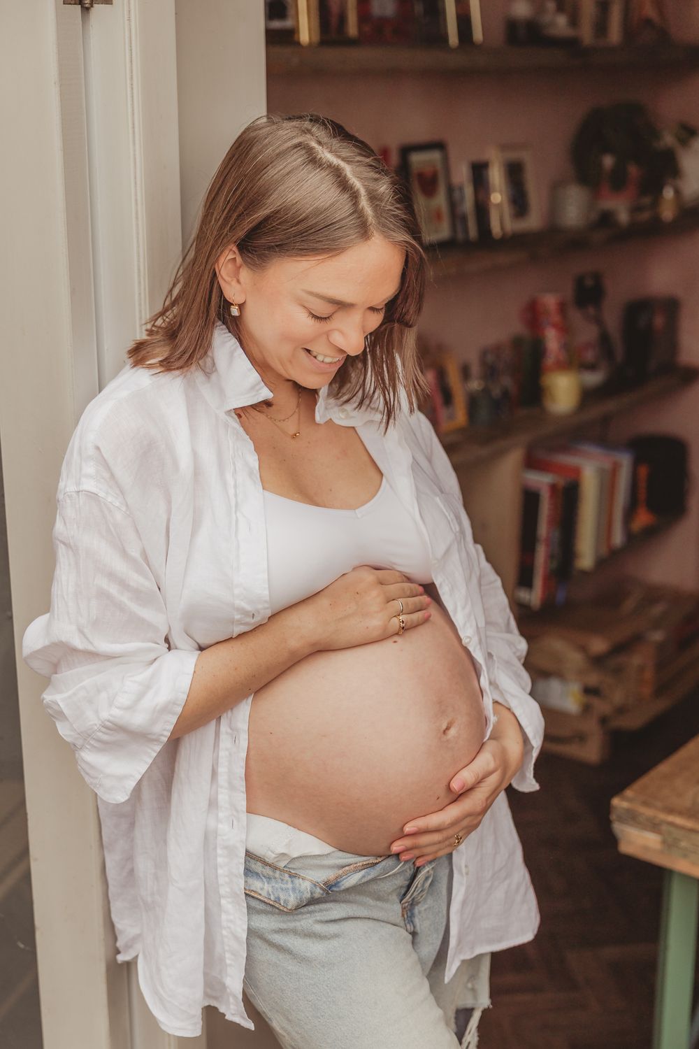 Series of intimate maternity photos showing pregnant woman in white shirt and jeans embracing her baby bump.