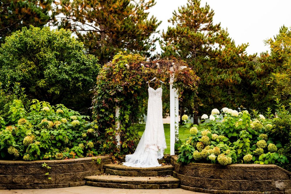 A row of white obelisk monuments stand among lush green trees and landscaping in a garden setting.
