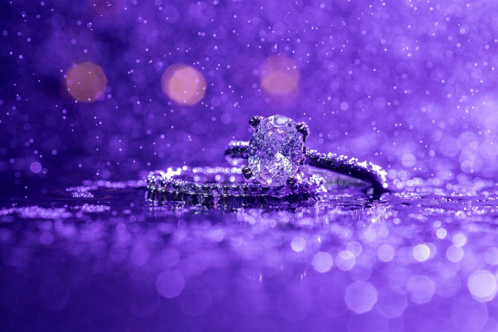 Sparkling purple bokeh lights create a dreamy abstract background with water droplets and reflective surfaces.