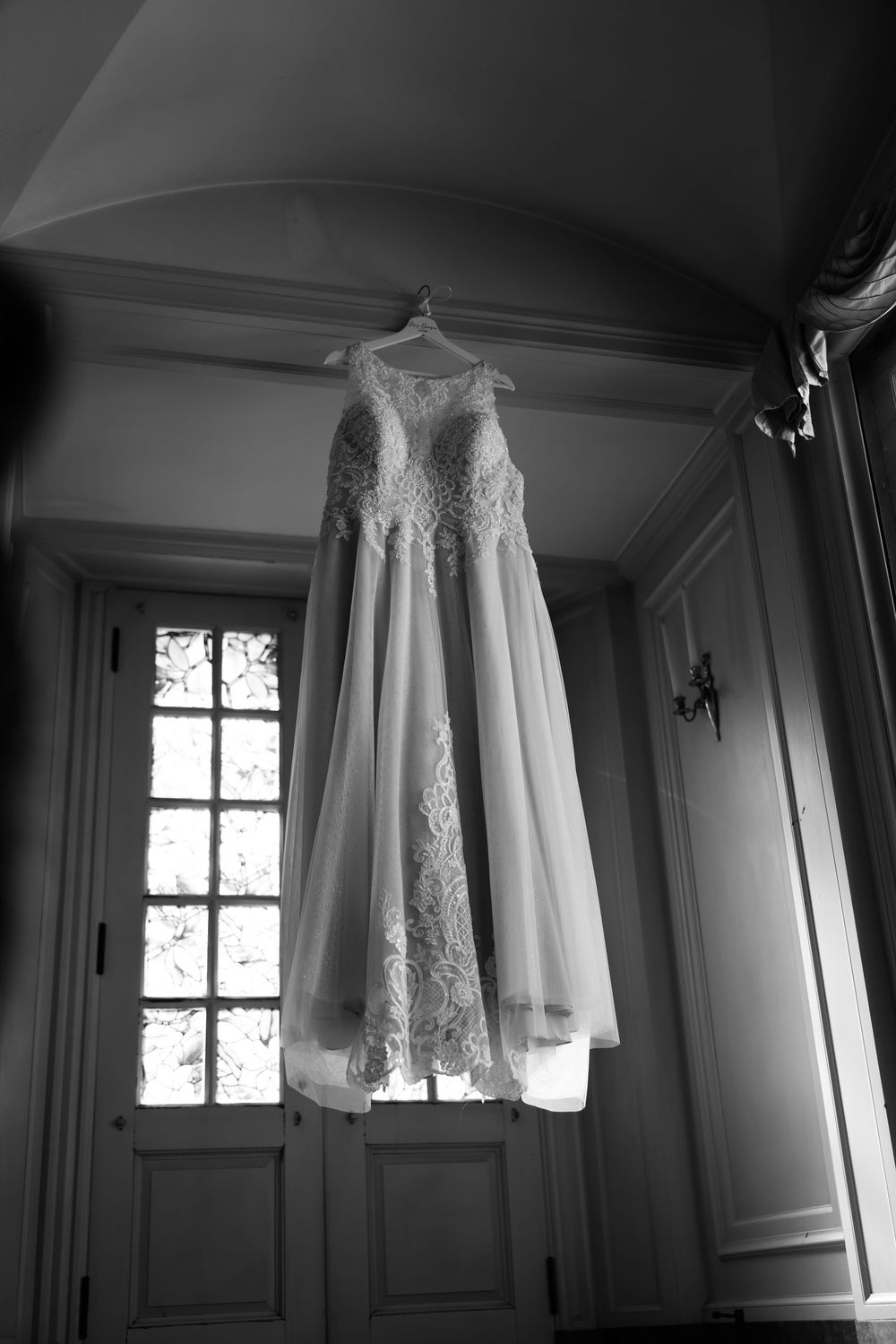 Wedding gown displayed in dramatic window lighting with architectural details.