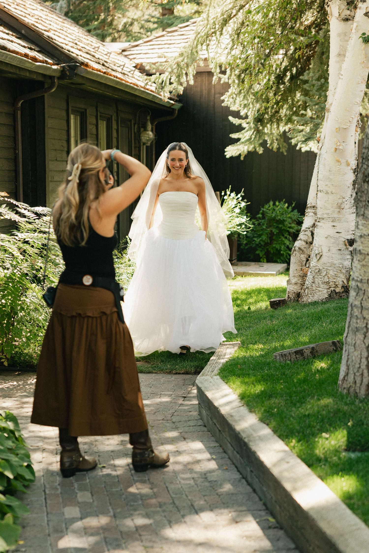 A sequence of four photos showing bridesmaids in brown dresses walking with a bride in a white gown along a garden path.