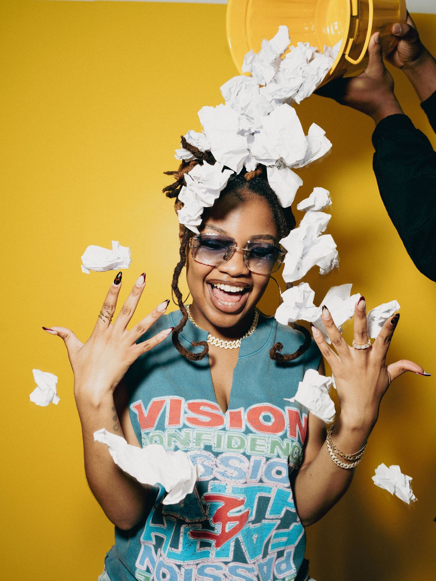 A series of joyful photos against a yellow wall showing someone playfully tossing crumpled paper in the air.