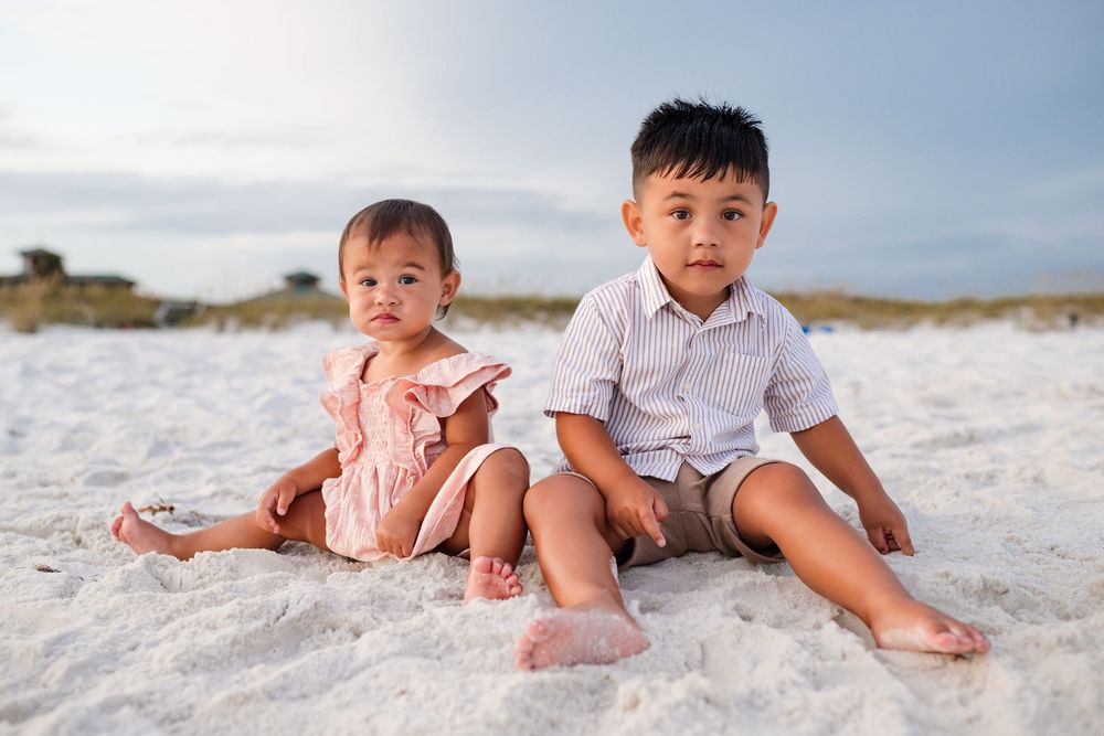 Children playing together on a pristine white sandy beach during a sunny day at the seashore.