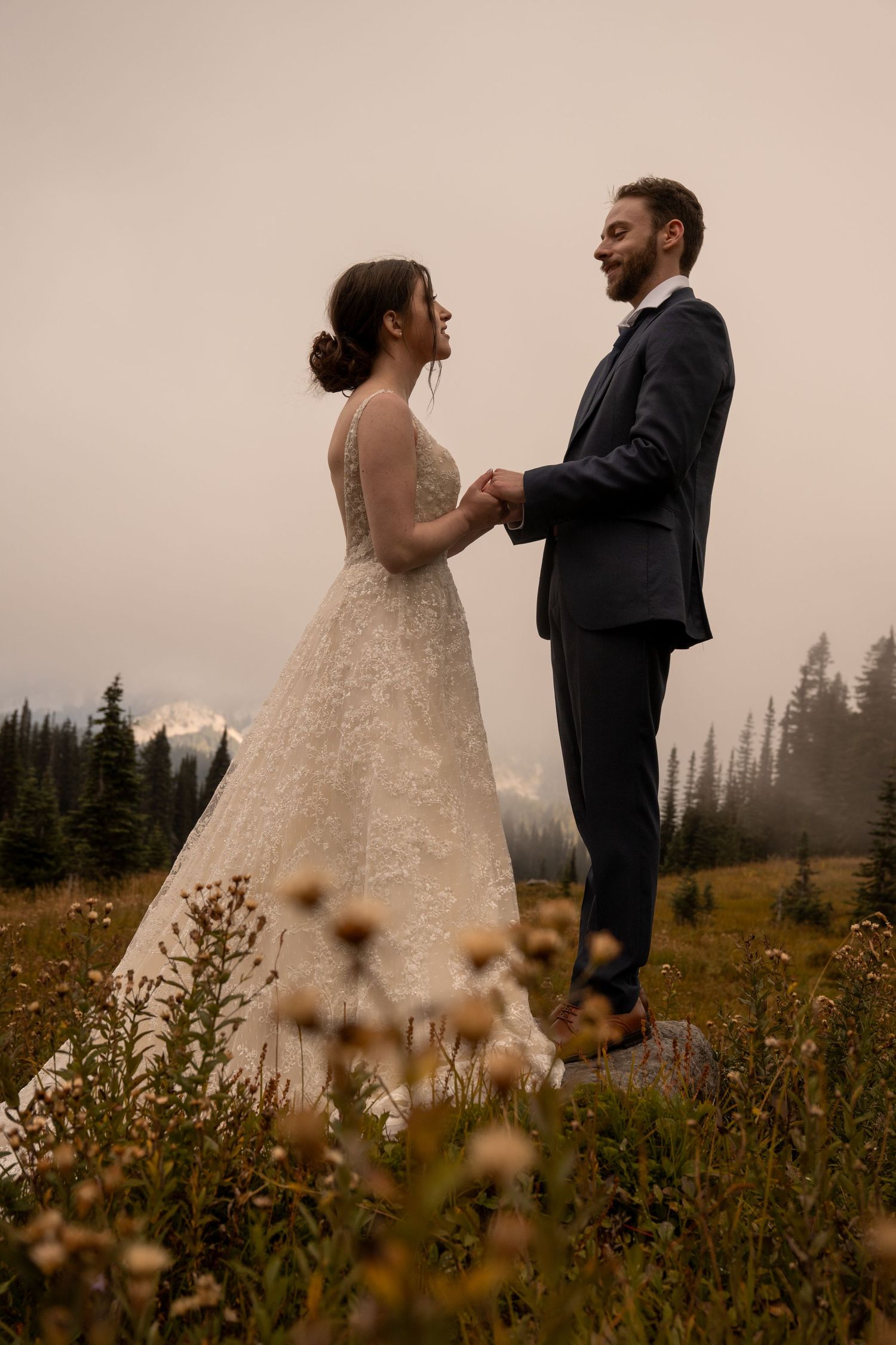 A young couple holds hands in an autumn field on a moody day near Paradise in Mt. Rainier National Park.