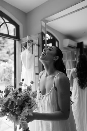Black and white photo series showing joyful moments of laughter and celebration with flowers in an indoor setting.