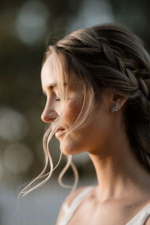 Artistic side profile portraits of a woman with windswept blonde hair and an earring at sunset.
