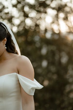 A white off-shoulder wedding dress detail shown in a series of cropped photos with bokeh background lighting.