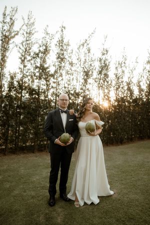 Wedding ceremony taking place outdoors at sunset with pine trees in the background.