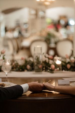 Wedding reception table settings with blurred bokeh lights and elegant floral centerpieces in warm ambient lighting.