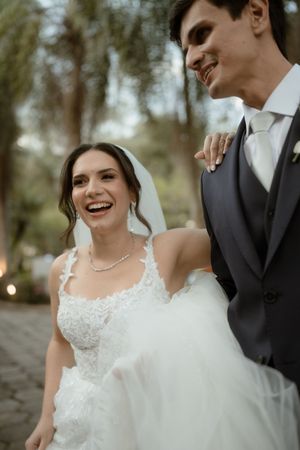 A joyful wedding moment captured outdoors with the bride in a lace gown and groom in classic charcoal suit.