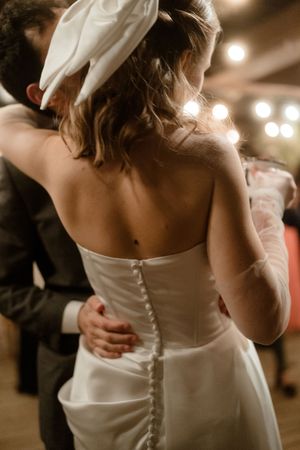 Close-up view of a white wedding dress with button details down the back during a reception dance.