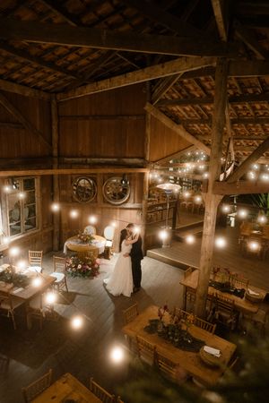 Rustic barn wedding venue illuminated by warm string lights creating a romantic atmosphere during an evening celebration.